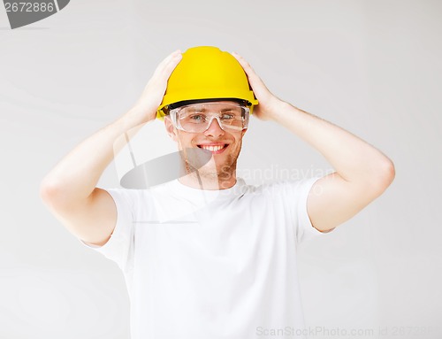 Image of male builder in safety glasses and yellow helmet