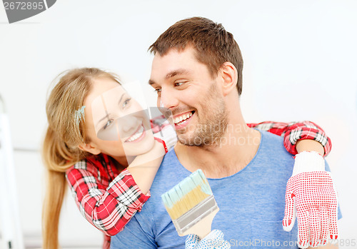 Image of smiling couple covered with paint with paint brush