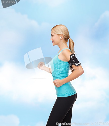 Image of sporty woman running with smartphone and earphones