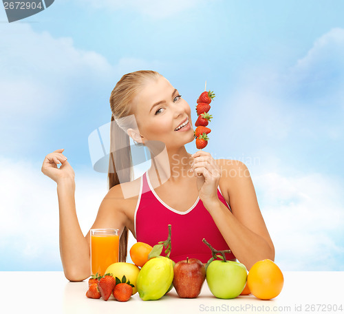 Image of smiling woman with organic food eating strawberry