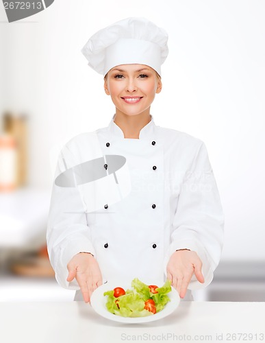 Image of smiling female chef with salad on plate