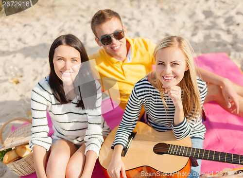 Image of group of friends with guitar having fun on beach