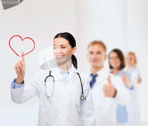 Image of smiling female doctor pointing to heart