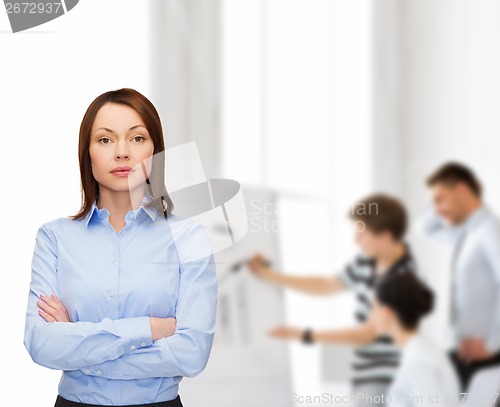 Image of smiling businesswoman with crossed arms at office
