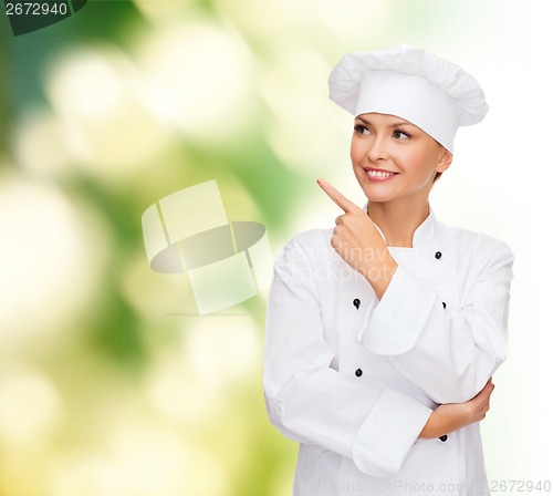 Image of smiling female chef pointing finger to sonething