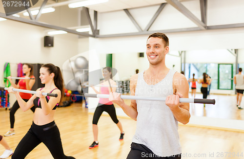 Image of group of smiling people working out with barbells