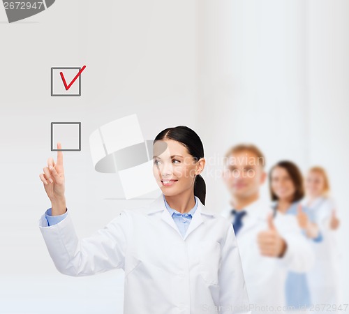 Image of smiling female doctor pointing checkbox