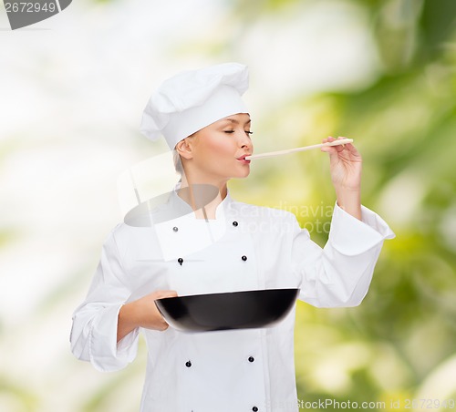 Image of smiling female chef with pan and spoon