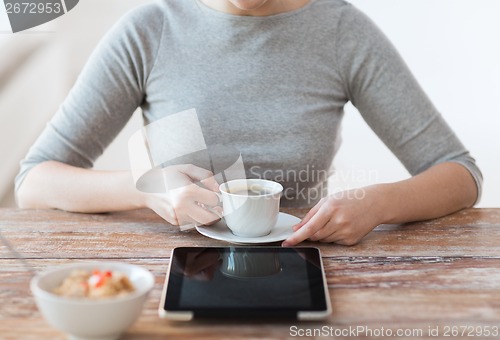Image of woman drinking coffee and using tablet pc