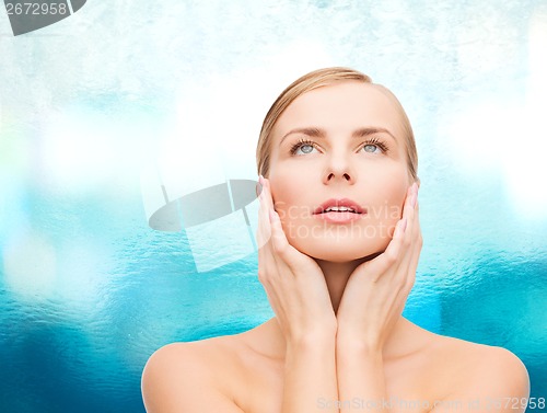 Image of beautiful woman touching her face and looking up