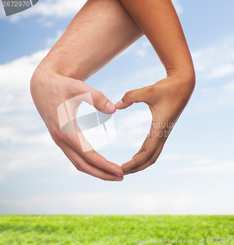 Image of woman and man hands showing heart shape