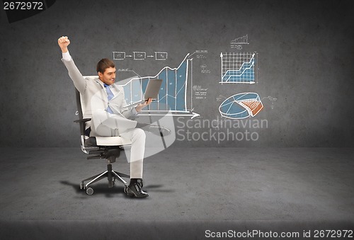 Image of young businessman sitting in chair with laptop