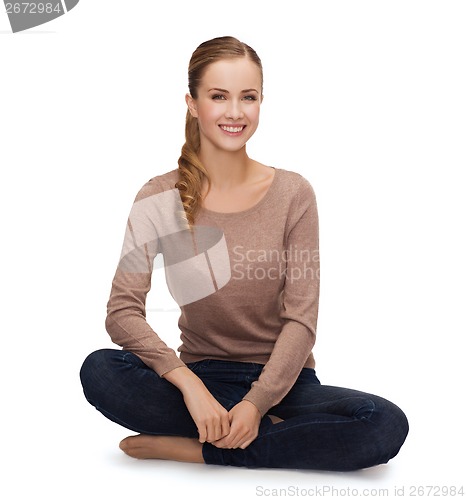 Image of smiling young woman sitting on floor