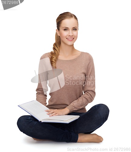 Image of smiling young woman sitting on floor