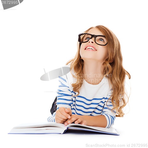 Image of girl with book and eyeglasses lying on the floor