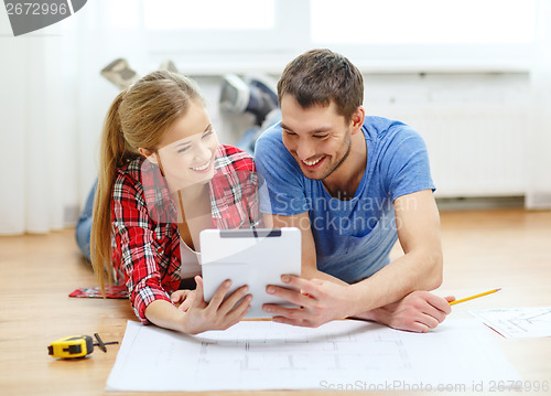 Image of smiling couple looking at tablet pc at home