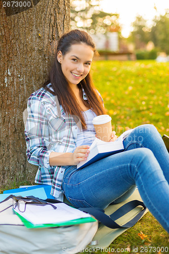 Image of teenager reading book with take away coffee