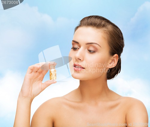 Image of beautiful woman showing bottle with golden dust