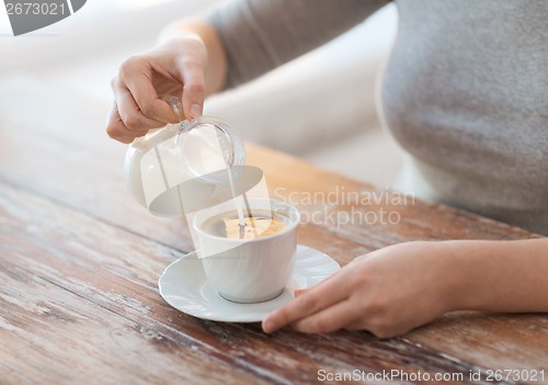 Image of close up of female pouring milk into coffee