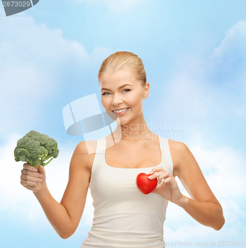 Image of smiling woman holding heart symbol and broccoli