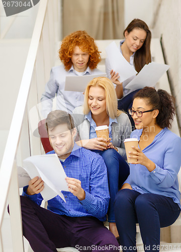 Image of team with papers and take away coffee on staircase