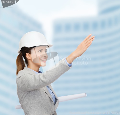 Image of smiling architect in white helmet with blueprints