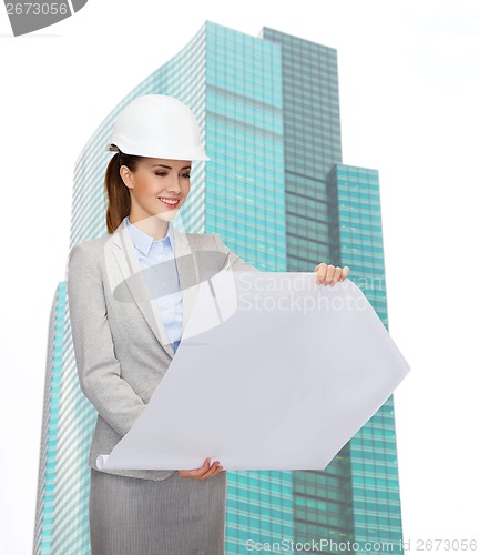 Image of smiling architect in white helmet with blueprints