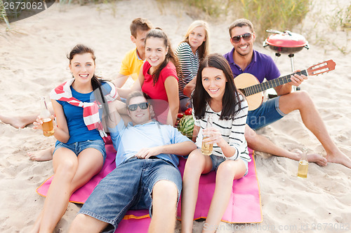 Image of group of friends with guitar having fun on beach