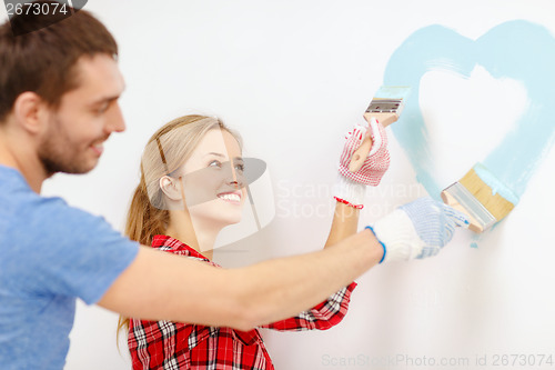 Image of smiling couple painting small heart on wall