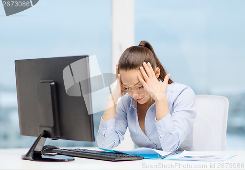 Image of stressed woman with computer and documents