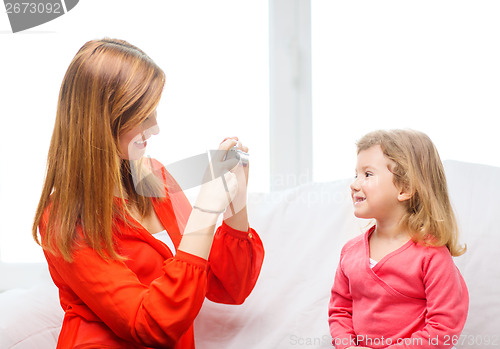 Image of smiling mother taking picture of daughter