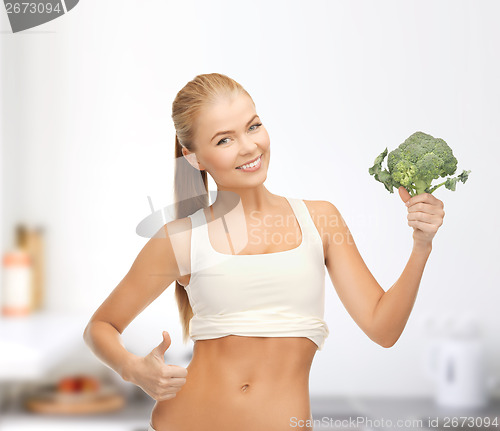 Image of woman pointing at her abs and holding broccoli