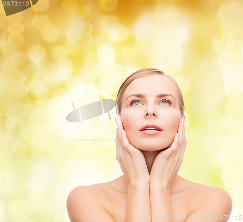 Image of beautiful woman touching her face and looking up