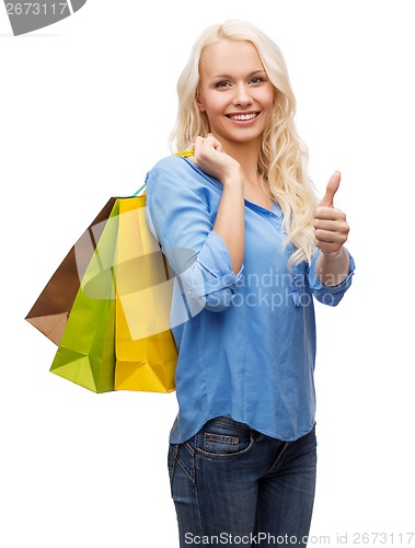 Image of smiling woman with shopping bags showing thumbs up