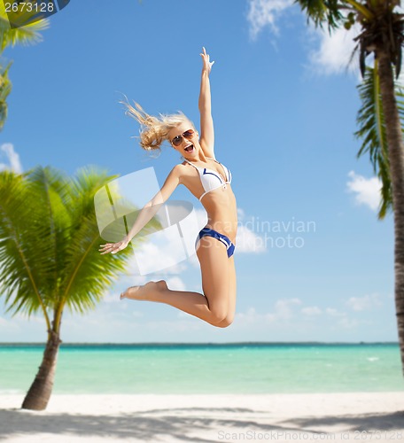 Image of laughing woman jumping on the beach