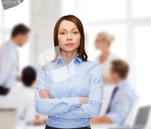 Image of smiling businesswoman with crossed arms at office