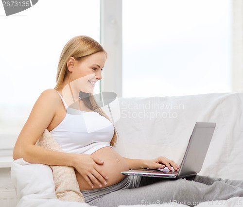 Image of smiling pregnant woman with laptop computer