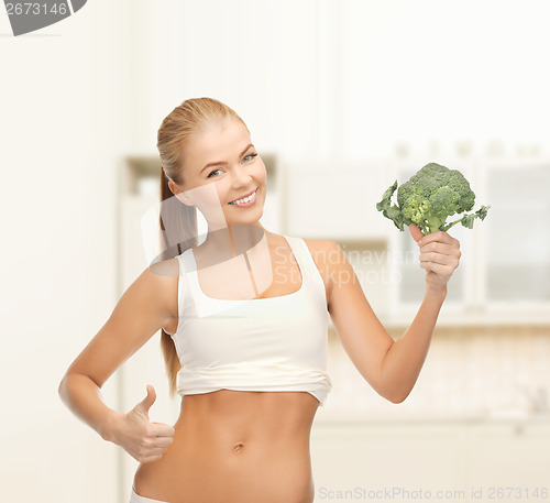 Image of woman pointing at her abs and holding broccoli