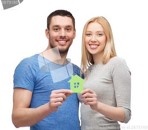 Image of smiling couple holding green paper house