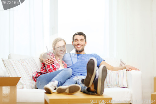 Image of smiling couple relaxing on sofa in new home