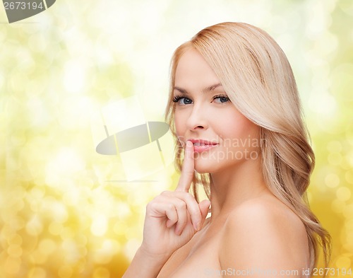 Image of beautiful young woman pointing finger to lips