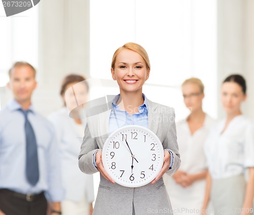 Image of smiling businesswoman with wall clock