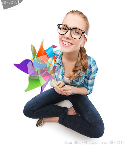 Image of woman in eyeglasses sitting on floor with windmill