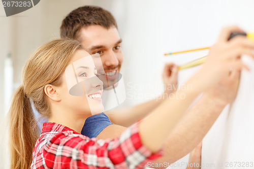 Image of smiling couple measuring wall