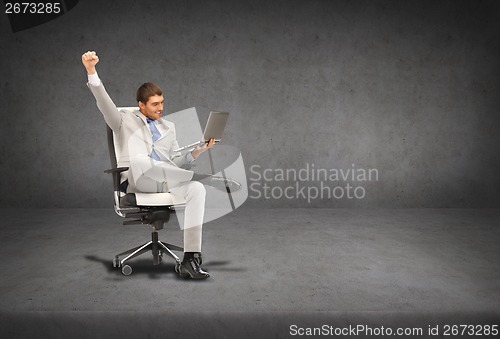 Image of young businessman sitting in chair with laptop