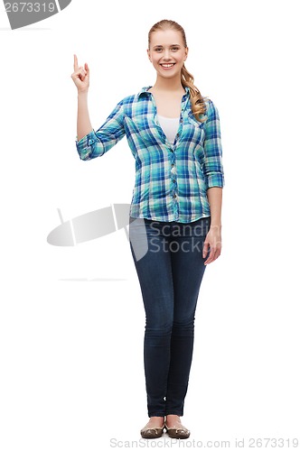 Image of smiling young woman pinting finger up