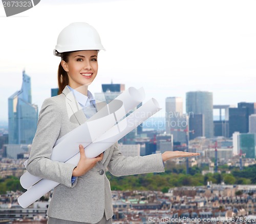 Image of smiling architect in white helmet with blueprints