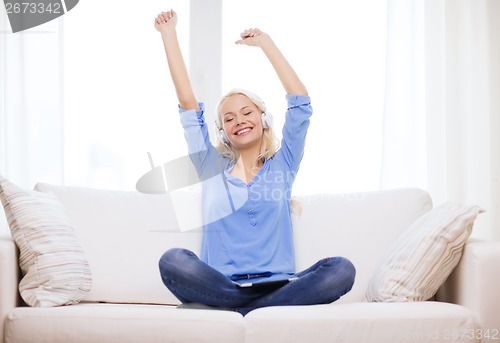 Image of woman with tablet pc and headphones at home