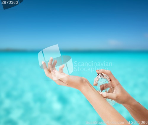 Image of woman hands spraying perfume