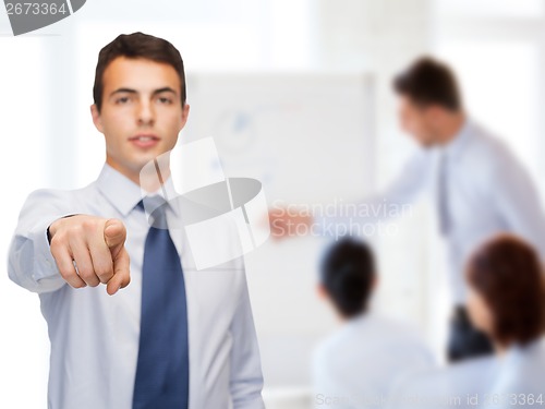 Image of friendly young buisnessman pointing finger